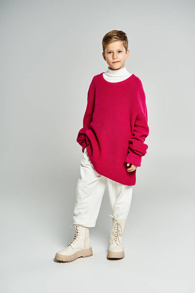 A boy happily showcases stylish winter clothing with a bold sweater and comfortable pants.