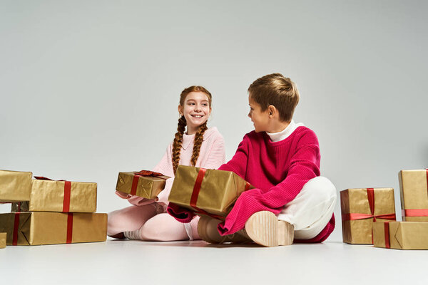 Дети с яркими улыбками наслаждаются разворачивающимися подарками во время зимних праздников.