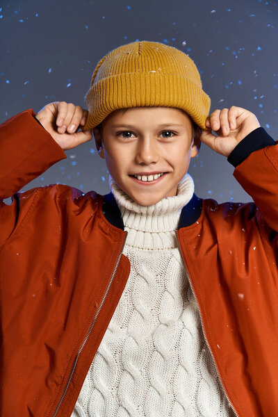 The boy beams with joy as he wears a knitted sweater and colorful beanie in a snowy setting.
