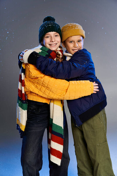 Two cheerful children wearing colorful winter clothing share a warm hug, celebrating togetherness.
