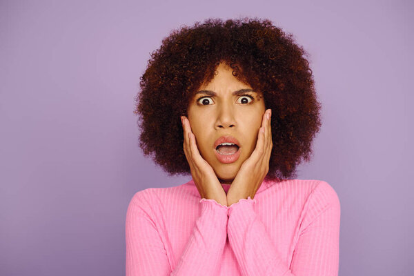 A young woman in pink clothing showcases her emotions, hands on her face, with a lively purple backdrop.