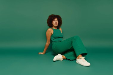 Bu kendine güvenen kadın, parlak yeşil bir zemine oturmuş günlük giysiler içinde..