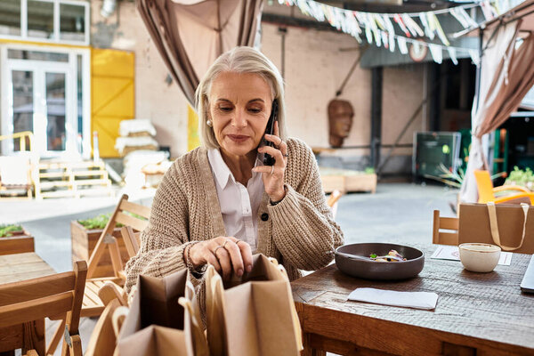 The lovely woman with gray hair chats on the phone and organizes her meal bags in a cozy setting.