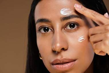 Bir kadın stüdyo ortamında güzellik çeşitliliğini vurgularken vücut bakımı ürünleri uygular.