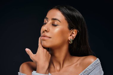 A woman highlights her beauty and jewellery while posing gracefully in a studio. clipart