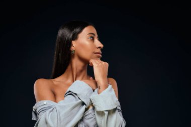 Esmer saçlı güzel bir Afro-Amerikalı kadın düşünceli bir şekilde stüdyoda poz veriyor..