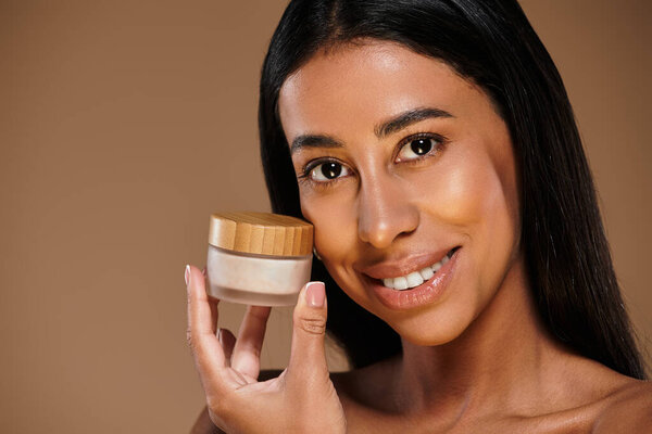 Женщина с брюнетками представляет продукт по уходу за кожей во время продвижения ухода за телом.