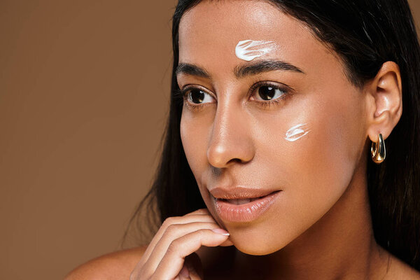 Женщина выделяет свою рутину по уходу за кожей, позируя в хорошо освещенной студии.