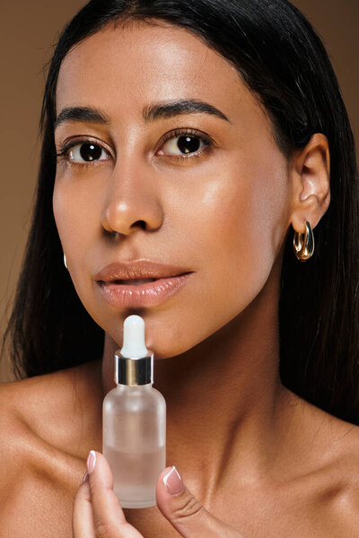 Женщина с брюнетками наносит кожу сыворотки, демонстрируя свою красоту в студии.