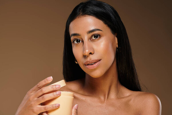 Красивая афроамериканка демонстрирует технику ухода за кожей в студии.