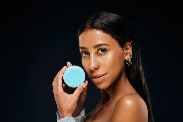 Женщина подчеркивает свою рутину по уходу за кожей во время позирования с продуктом по уходу за телом в студии.