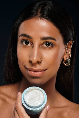 A woman highlights her skincare routine while demonstrating body care in a studio setting. clipart