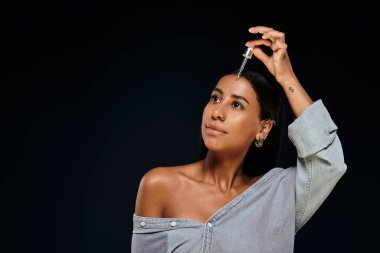 Stüdyodaki Afrikalı Amerikalı kadın cildine serum ekliyor, güzellik ve vücut bakımını gösteriyor..