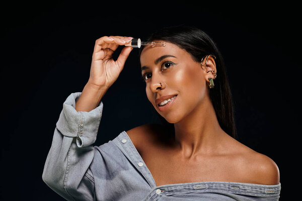 Женщина с брюнетками демонстрирует рутину по уходу за кожей в студии, применяя сыворотку.