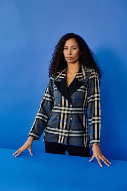 Zarif bir kadın, modern bir ortamda elleri masanın üzerinde güven içinde durur.