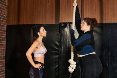 Kadınlar, halat tırmanışı içeren zorlu bir fitness rutininde başarılı olmak için birbirlerini zorluyorlar..