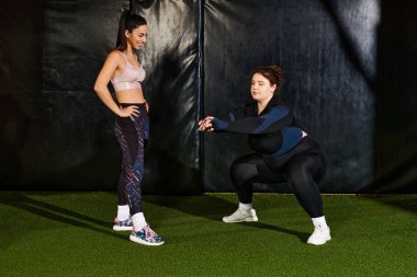İki kadın spor salonunda destek egzersizi yapar, azim ve enerji gösterisi yapar..