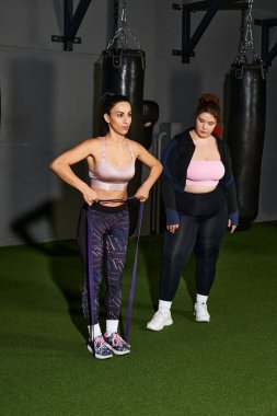 Kadınlar egzersiz sırasında iyi donanımlı bir spor salonunda direnç bantlarıyla egzersiz yaparlar..