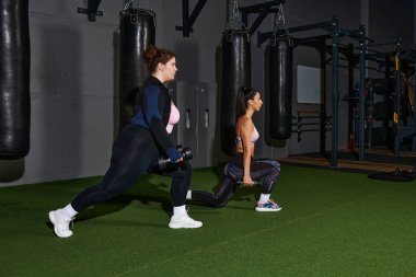 Modern bir spor salonunda ağırlıklarla hareket eden iki kadın spor salonuna odaklandı..