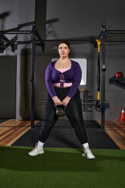Odaklanmış kadın vücut geliştirme ve dayanıklılığını artırırken kettlebell egzersizleri yapıyor..