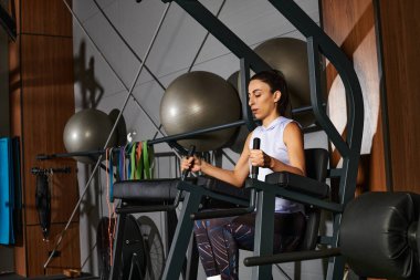 İyi donanımlı, çağdaş bir spor salonunda otururken odaklanmış güç egzersizleri yapmak..