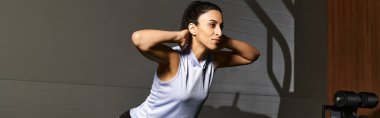Kendini adamış bir kadın sabah saatlerinde şık bir spor salonunda dinamik bir egzersiz yapıyor..
