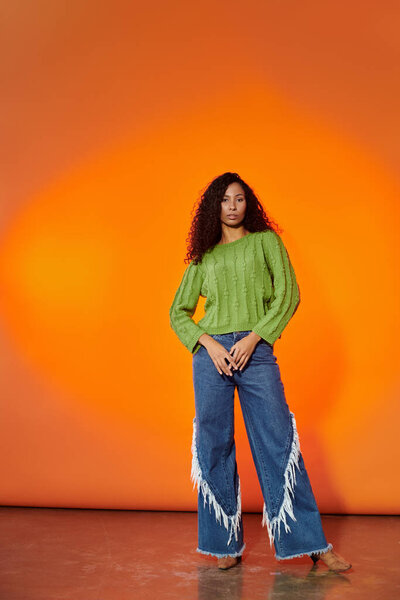 Потрясающая женщина излучает уверенность в зеленом свитере и стильных джинсах.