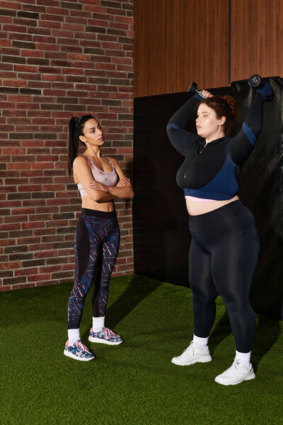 Two women engaged in a focused workout, showcasing strength and encouragement in the gym.