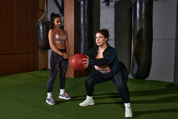 Две женщины упорно тренируются, используя взвешенный мяч, чтобы вместе повысить силу и выносливость..