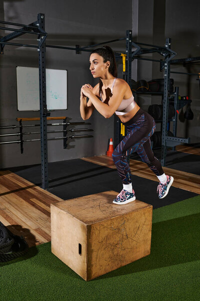 Female woman performs an explosive box jump on a sturdy platform in a fitness studio.