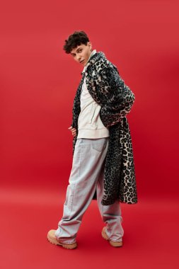 Yakışıklı adam, leopar desenli ceketi ve rahat pantolonuyla cesur moda seçimleri sergiliyor..
