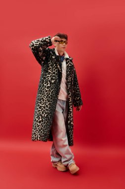 Yakışıklı bir adam moda leopar desenli ve şık aksesuarlı bir ceketle rahatça poz veriyor..