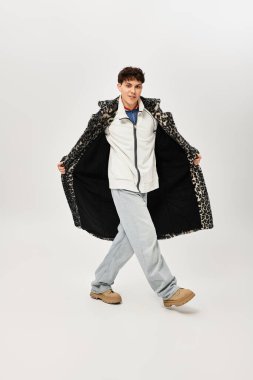 Yakışıklı bir adam, parlak, basit bir stüdyo dairesinde rahatça poz verirken modaya uygun kıyafetler giyer..