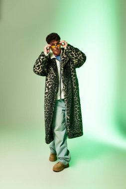 Yakışıklı bir adam leopar desenli bir ceket ve şık aksesuarlarla karizma yayar, poz verir..