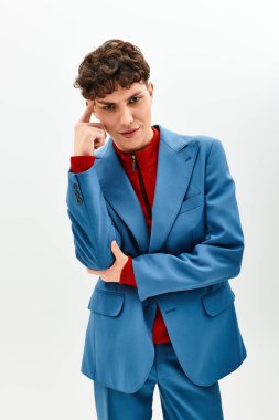 Yakışıklı adam, altında kırmızı bir kazak ve şık mavi bir takım elbiseyle modern moda sergiliyor..