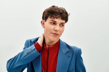 Şık bir genç adam modern bir görünüm sergiliyor, parlak bir ortamda boynunu şakayla düzeltiyor..