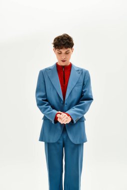 Handsome man dressed in a blue suit and red sweater captivatingly poses in a clean, bright space. clipart