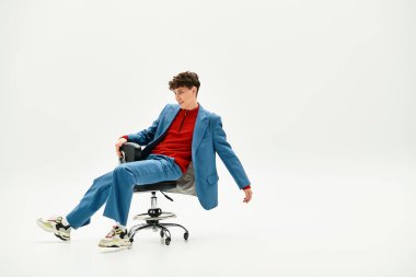 Yakışıklı bir adam ofis sandalyesinde dinlenirken modern moda anlayışını sergiliyor..