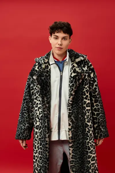 Yakışıklı bir adam, leopar desenli bir ceketle cesur kırmızı bir duvara yaslanır..