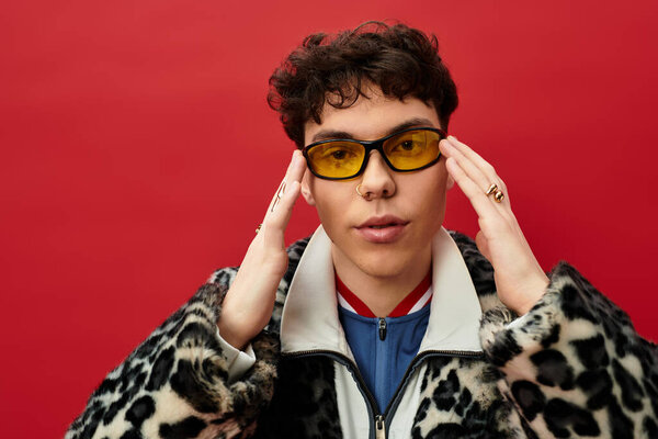 Красивый человек обнимает смелый стиль с уникальным выбором моды и игривые солнцезащитные очки.