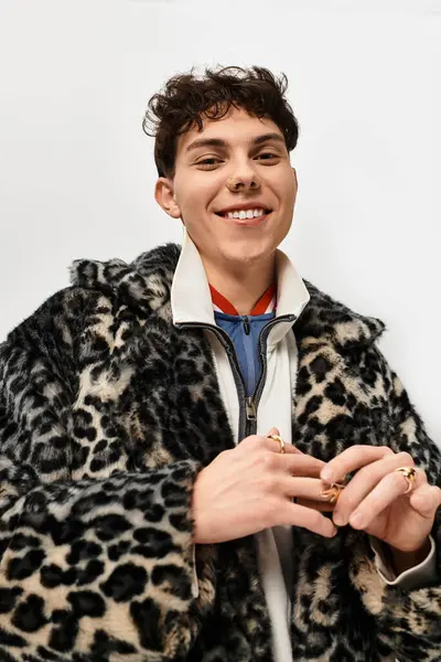 Şık bir adam kendine güvenerek ayakta duruyor, çarpıcı bir leopar desenli bir ceket giyiyor ve sıcak tutuyor..