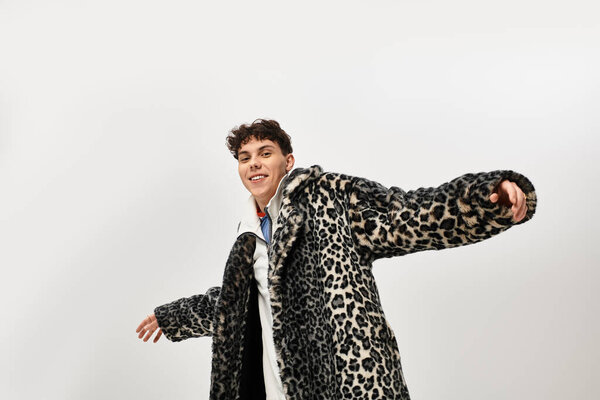 Стильный мужчина с радостью позирует в модном леопардовом пальто в современной обстановке.