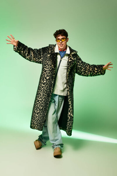 Stylish man showcases vibrant outfit in a colorful studio, exuding confidence and flair.