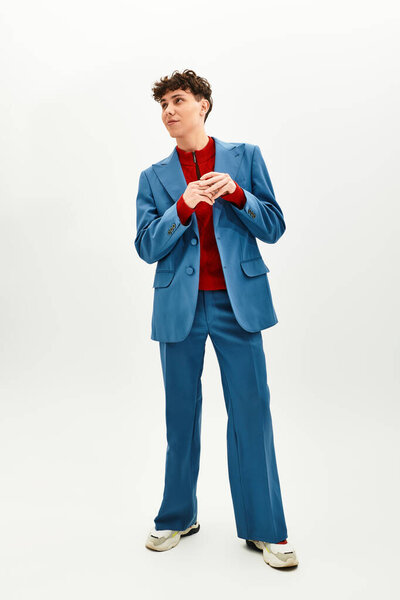 Handsome man in a blue suit and red shirt poses confidently against a clean backdrop.