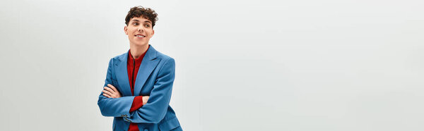 Красивый мужчина демонстрирует модный наряд, стоя со скрещенными руками, улыбаясь.