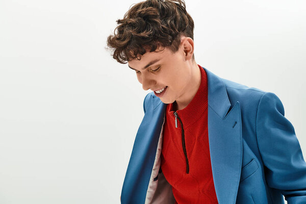 Красивый мужчина в синем костюме улыбается, регулируя свой наряд в минималистском пространстве..