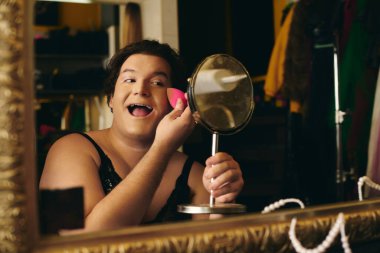 Bir travesti, sahne arkasında canlı bir makyaj yapar ve bir tatil gösterisine hazırlanır..