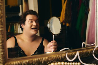 Bir travesti aynanın yanına makyaj yapar, sahne arkasında canlı bir tatil gösterisi için hazırlanır..