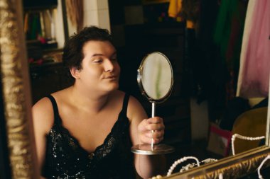 Yetenekli bir travesti, neşeli bir gösteriden önce makyaj yapar. Heyecan ve yaratıcılık saçar..