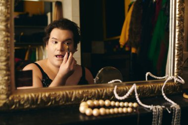 Sahne arkasındaki soyunma odasında bir travesti, bir tatil gösterisinden önce makyajını mükemmelleştirir..